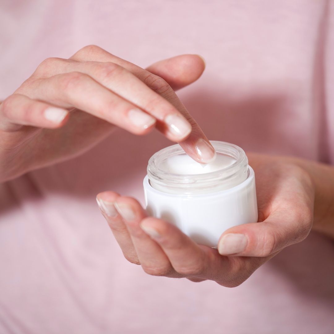 Person dipping a finger into moisturizer.